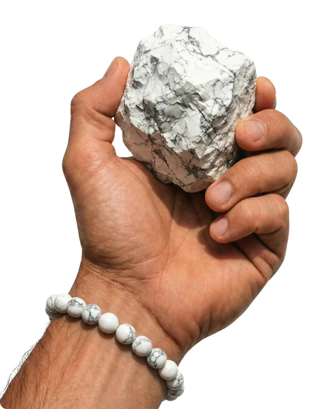 Gros plan sur une main d'homme tenant un bloc de howlite brute blanche et montrant un bracelet de perles de howlite assorties.