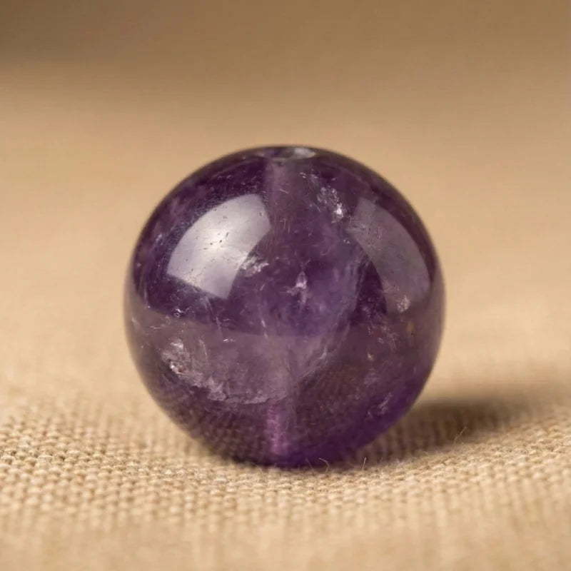 Perle d'améthyste naturelle en gros plan. Pierre fine véritable aux tons violets et reflets translucides pour la création de bijoux authentiques.