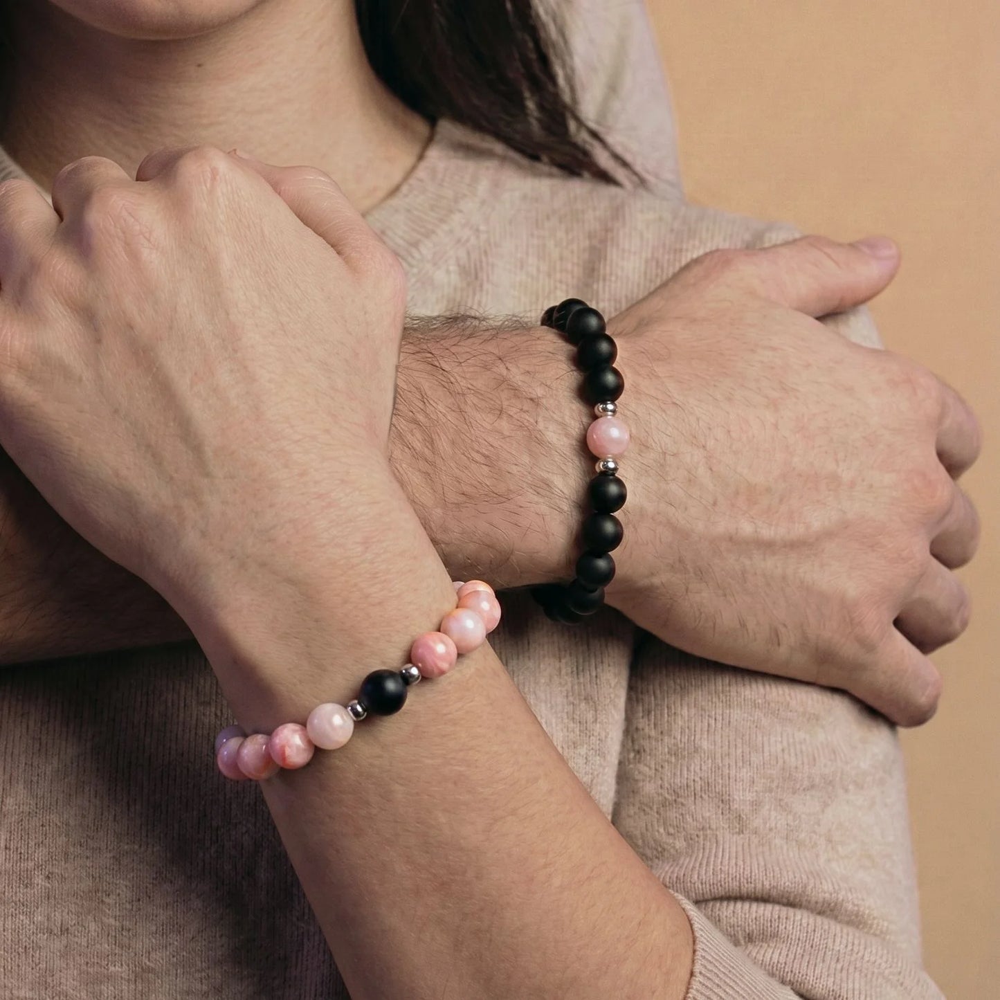 Couple enlassé et portant le duo de bracelets couple assortis rose et noir AMORE de Antaluna