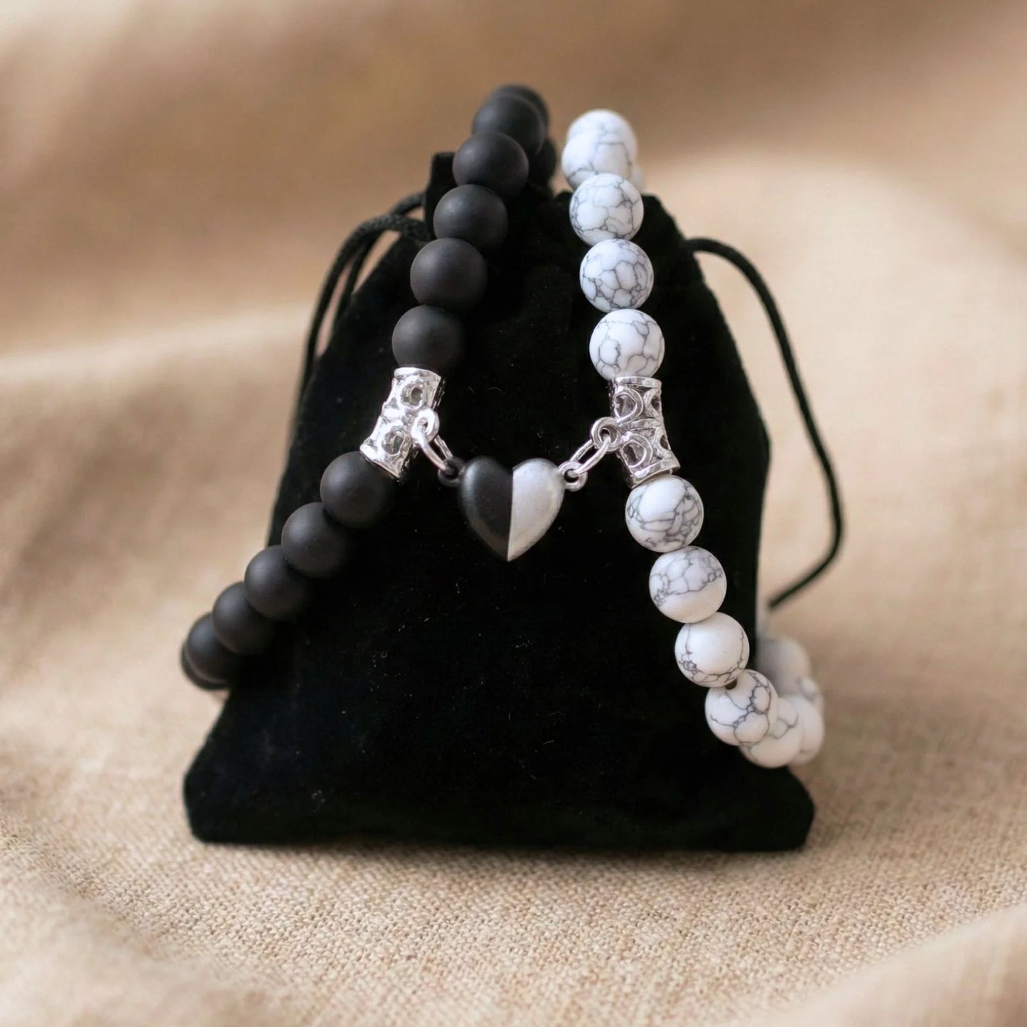 Bracelet couple AMORE en Howlite et Onyx posé sur un pochon noir.