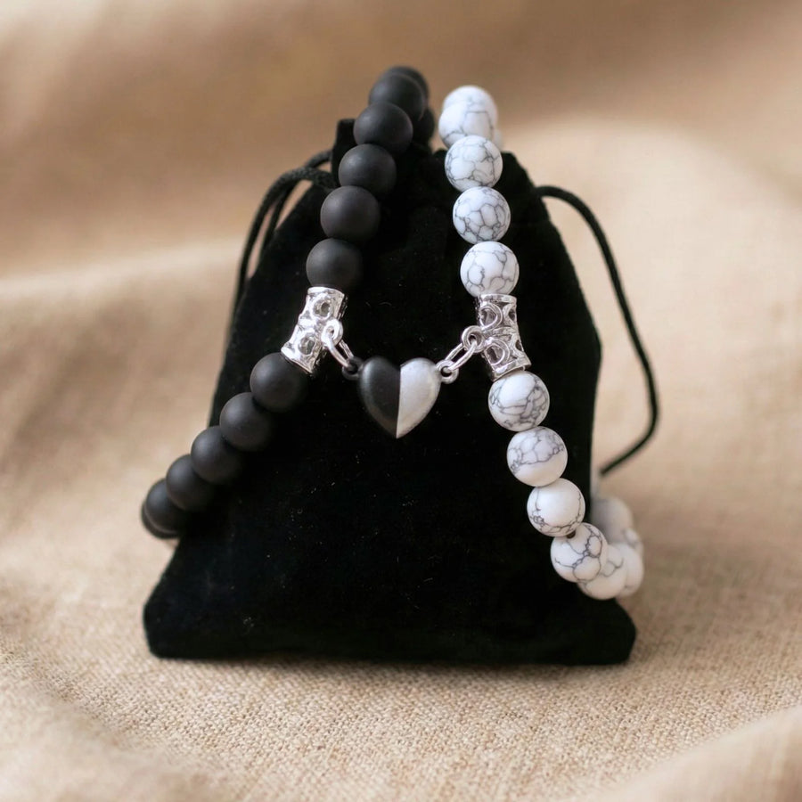 Bracelet couple AMORE en Howlite et Onyx posé sur un pochon noir.