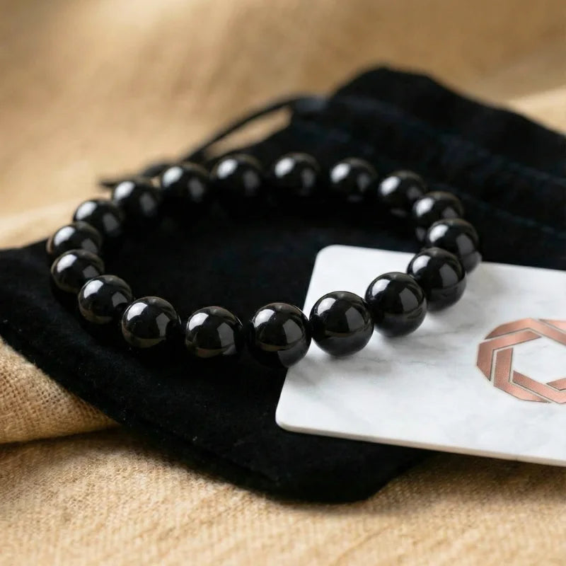 Bracelet en perles d'Onyx noir naturel posé sur sa pochette de protection en velours noir, accompagné de sa carte d'authenticité Antaluna.
