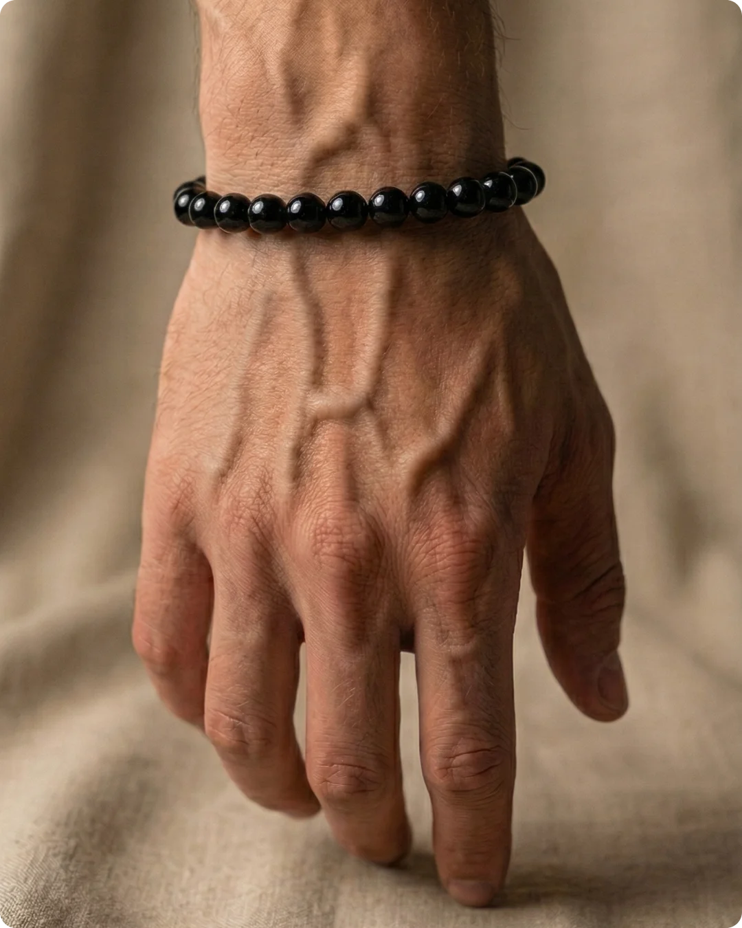 Gros plan sur un poignet masculin portant un bracelet homme en pierre naturelle noire en perles d'onyx.