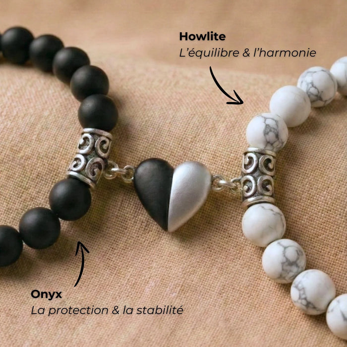 Macro sur le coeur aimanté des bracelets couple distance AMORE blanc et noir avec des flèches décrivant la symbolique des pierres.